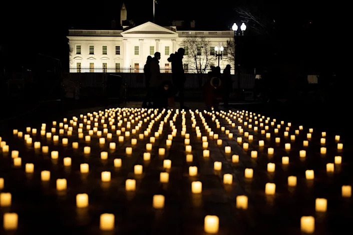 People walk past electric candles from a vigil in Lafayette Park oin Washington, D.C., for nurses who died during the COVID-19 pandemic.
