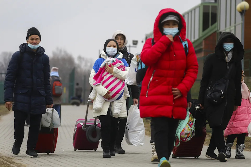 Civilians from Ukraine pull wheeled suitcases behind them after crossing the Ukraine-Poland border. 